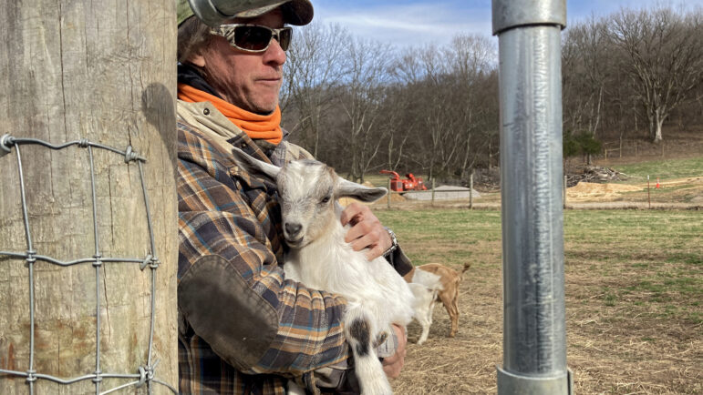 Chris Gramling cradles one of his goats while leaning against a fence post on his farm in Culleoka, Tennessee.