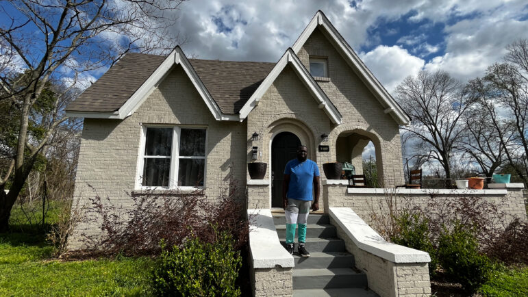 man stands in front of house