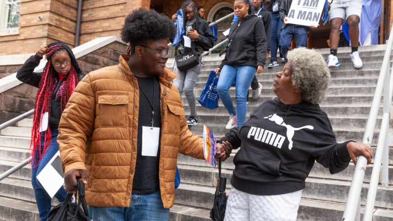 young man helps older woman down stairs