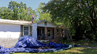 A construction crew tears off the roof of the home of Karen Ellis in Loxley, Alabama, on April 20, 2023