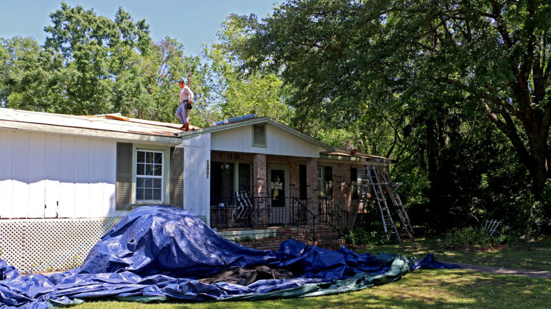 A construction crew tears off the roof of the home of Karen Ellis in Loxley, Alabama, on April 20, 2023