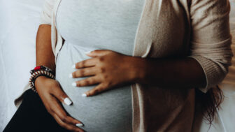 In this stock image, a pregnant Black woman holds her stomach.