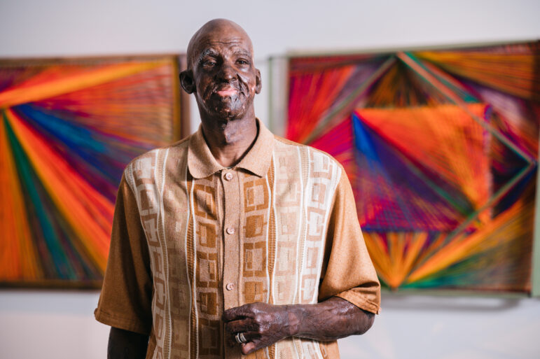 Delrico Gibson poses in front of his artwork at UAB’s Abroms-Engel Institute for Visual Arts.
