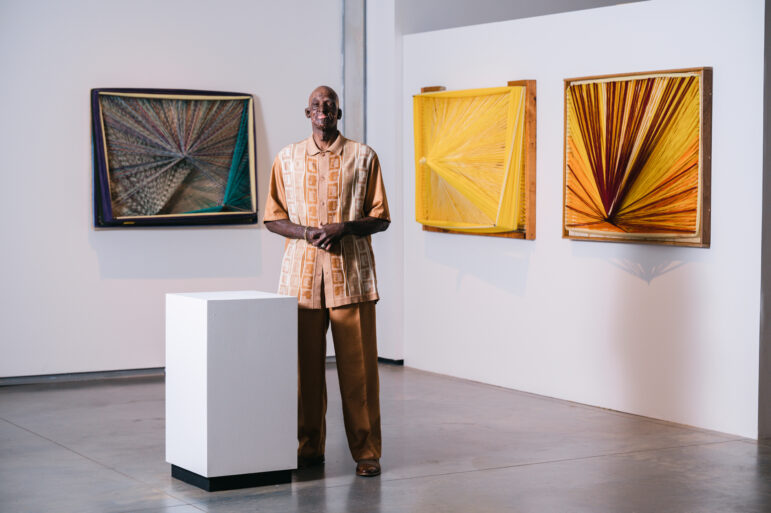 Delrico Gibson poses in front of his artwork at UAB’s Abroms-Engel Institute for Visual Arts.
