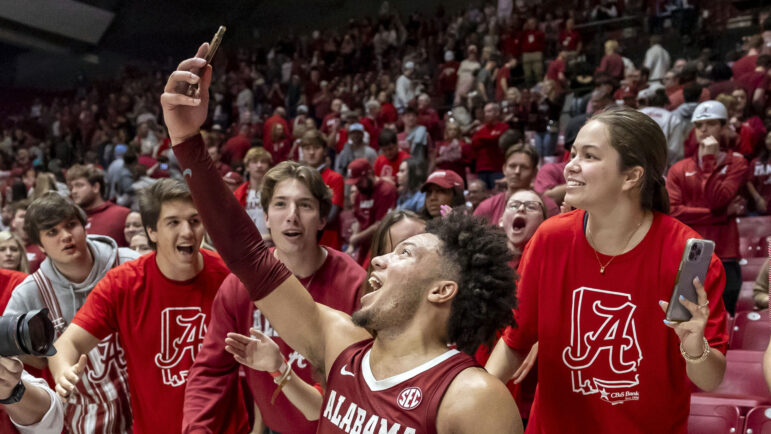 Alabama guard Mark Sears (1) takes a selfie as he celebrates with the student section after Alabama's overtime win over Arkansas in an NCAA college basketball game, Saturday, March 9, 2024, in Tuscaloosa, Ala.