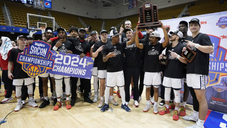 Samford guard Garrett Hicks, fourth from right, raises the championship trophy as he celebrates with teammates after their victory over East Tennessee State in the NCAA college basketball championship game for the Southern Conference tournament, Monday, March 11, 2024, in Asheville, N.C.