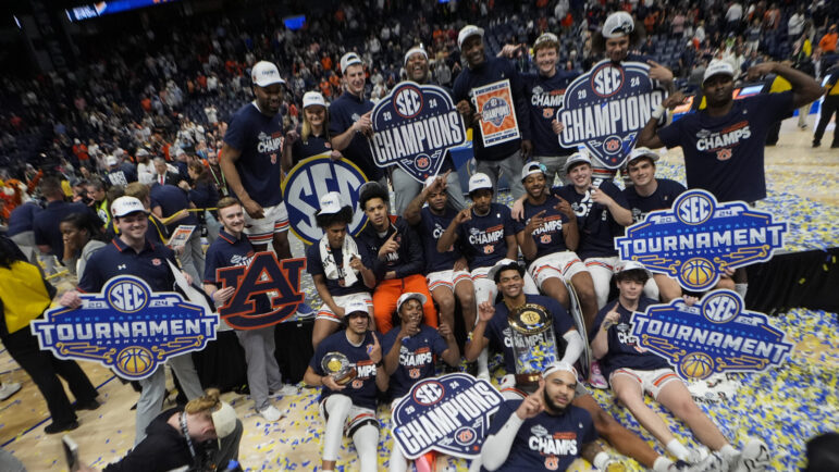 Auburn players pose for a team photo after defeating Florida in an NCAA college basketball game to win the Southeastern Conference tournament Sunday, March 17, 2024, in Nashville, Tenn.