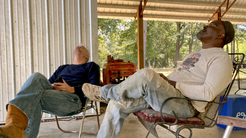 Andrew Freear (left) and Reggie Walker (right) sit under a floating roof constructed by the Rural Studio in Hale County, Alabama on Oct. 18, 2023.