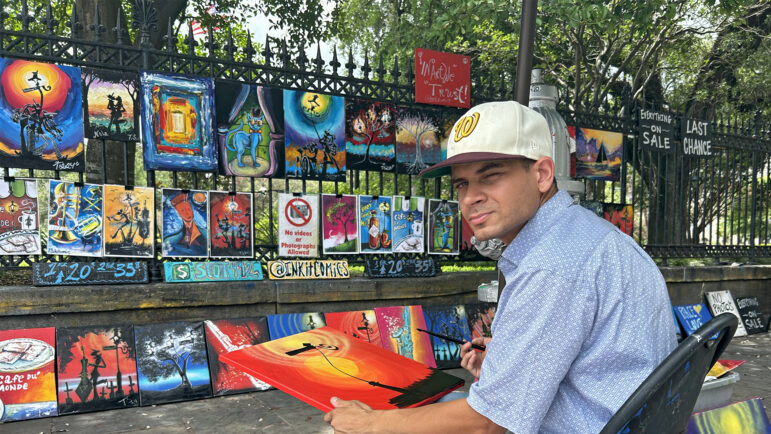 Artist Trevor Scott paints and sells his artwork in Jackson Square in New Orleans on June 26, 2024.