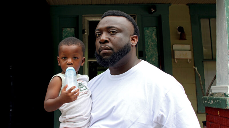 Carl Law and his son, Blaze, stand on a porch in the Lakeside neighborhood of Shreveport, Louisiana, on April 18, 2024.