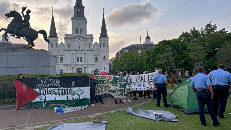 Pro-Palestinian protests hold signs and face New Orleans police officers in Jackson Square on April 28, 2024. Twelve people were arrested during the protest.