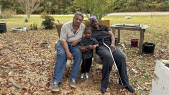 Willie and Thelma Perryman sit with their young grandson in the front yard of their home on Wednesday, October 30, 2024, in Letohatchee, Alabama.