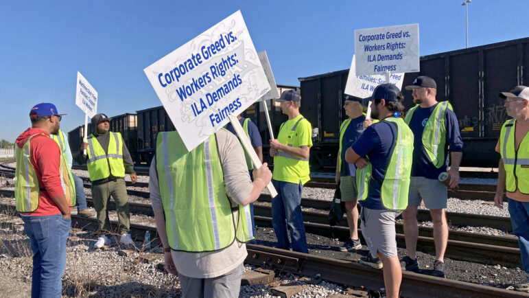 Dock works at the Port of Mobile picket outside the port as a train blocks their view of the terminal on October 1, 2024.