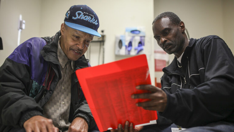 Community health worker Ron Sanders, right, helps a patient at San Francisco’s Southeast Family Health Center, part of the Transitions Clinic Network that assists former inmates navigate health care after release.