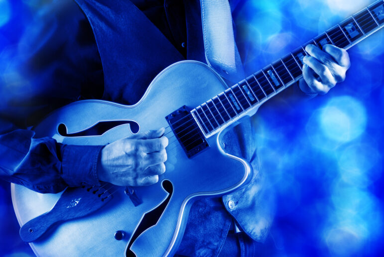 jazz guitarist playing guitar live on stage under blue light