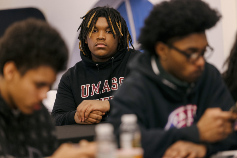 Gabriel Dorvil, 14, is shown looking directly at the camera. Other teenage boys are also in the frame, in a classroom setting.