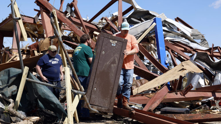 Friends and family members search for belongings in the damage after a tornado passed Plantersville, Alabama.