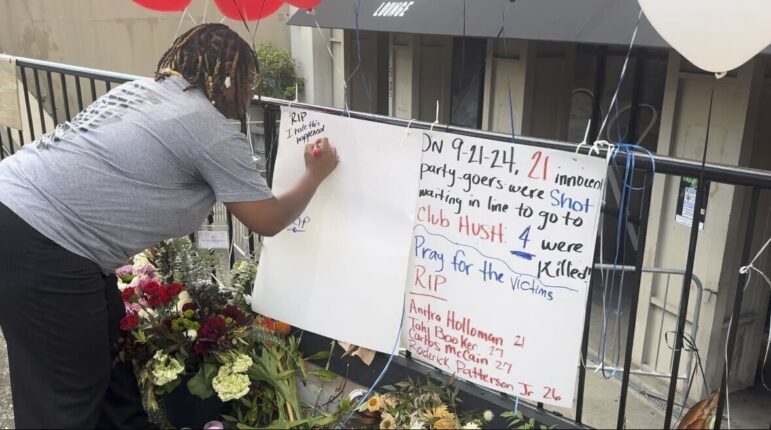 Nichole Smith signs a memorial sign remembering the four people who were killed in a shooting outside a nightclub in Birmingham.