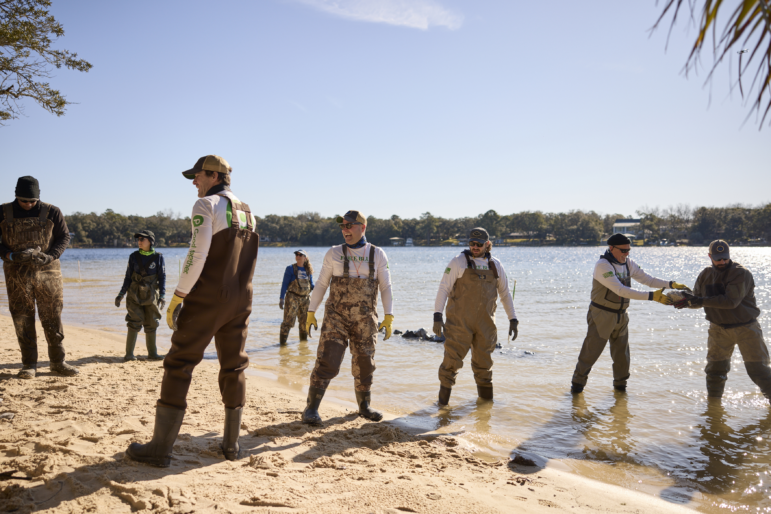 Veterans and volunteers with Force Blue use an assembly line to transport stones to build a rubble wall in Ft. Walton Beach, Fla.