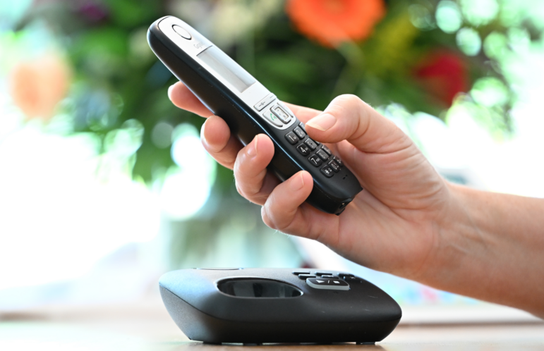 A photo of a person holding a landline phone.