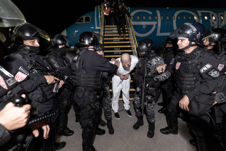 Guards escort one of the hundreds of alleged members of the 'Tren De Aragua' and Mara Salvatrucha gangs who were deported from the U.S. to El Salvador.