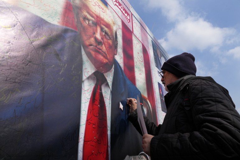 A man writes a slogan on a portrait of the U.S. President Donald Trump during a rally commemorating anniversary of Iran's 1979 Islamic Revolution that toppled the late pro-U.S. Shah Mohammad Reza Pahlavi and brought Islamic clerics to power, in Tehran, Iran, Monday, Feb. 10, 2025. Trump says the U.S. and Iran will have direct nuclear talks soon.