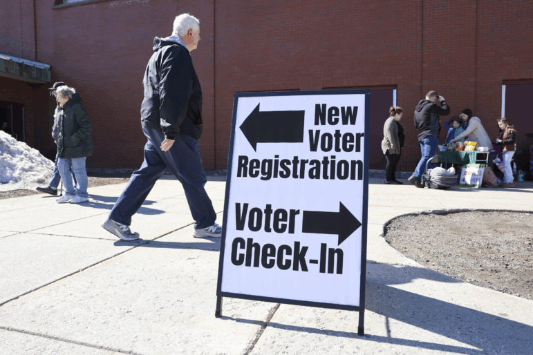 A sign for new voter registration is seen outside a polling location in Derry, N.H., on March 11.