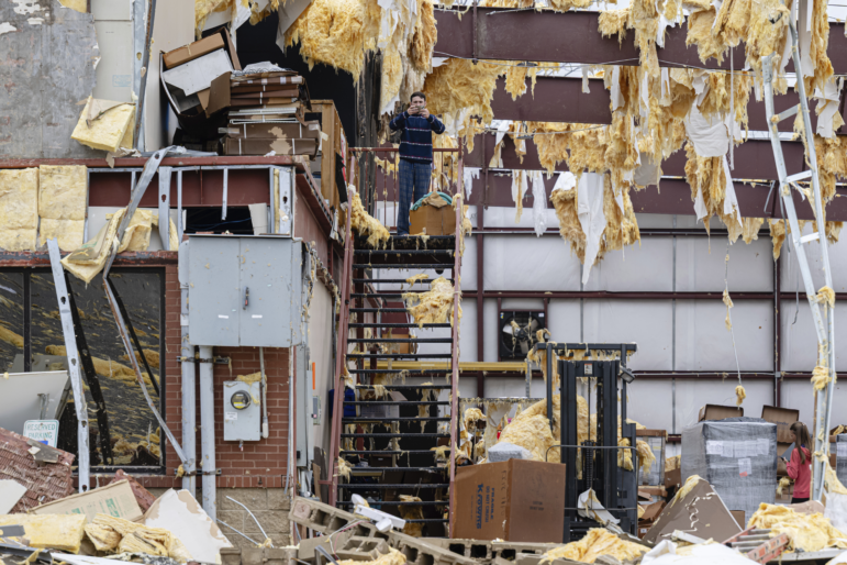William Fraser takes photographs inside the warehouse of a damaged building of Specialty Distributors after severe weather passed through an industrial park on Thursday in Jeffersontown, Ky. (AP Photo/Jon Cherry)