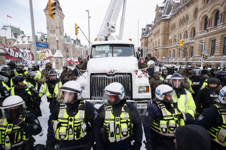 Police hang off a truck as authorities work to end a protest against COVID-19 measures in Ottawa on Feb. 19, 2022.