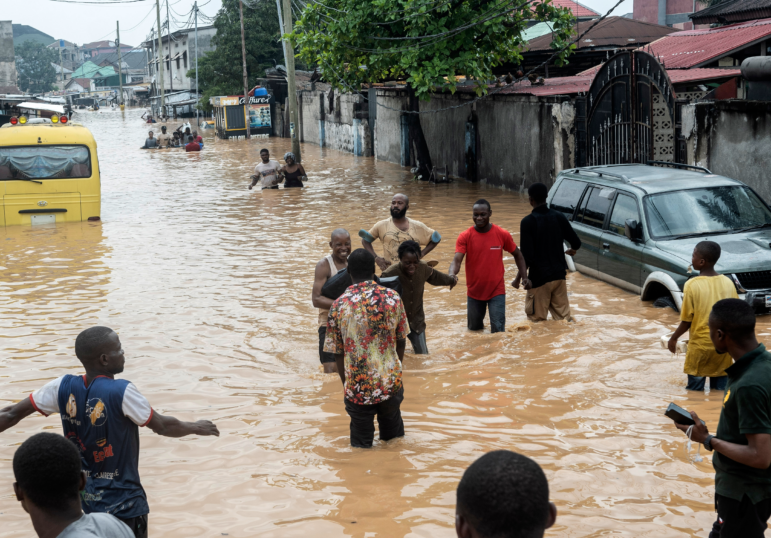 People walk through the flooded streets of Kinshasa, Democratic Republic of Congo on Sunday.