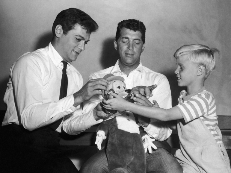 Jay North, young star of the new Dennis the Menace series, right, attempts to handcuff Dean Martin, center, as they play with a stuffed toy with Tony Curtis on Sept. 15, 1959.