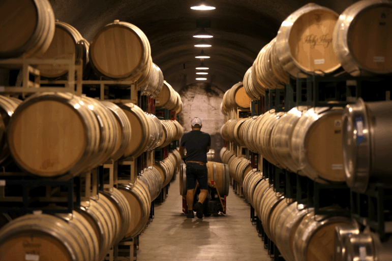 A worker pushes a wine barrel into a storage facility at Hunnicutt winery.