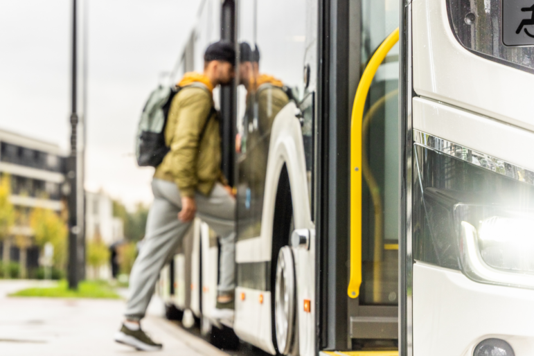 A man wearing a backpack boards a bus.
