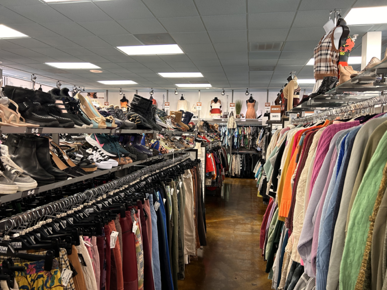 Racks of clothes and shoes inside a thrift store.