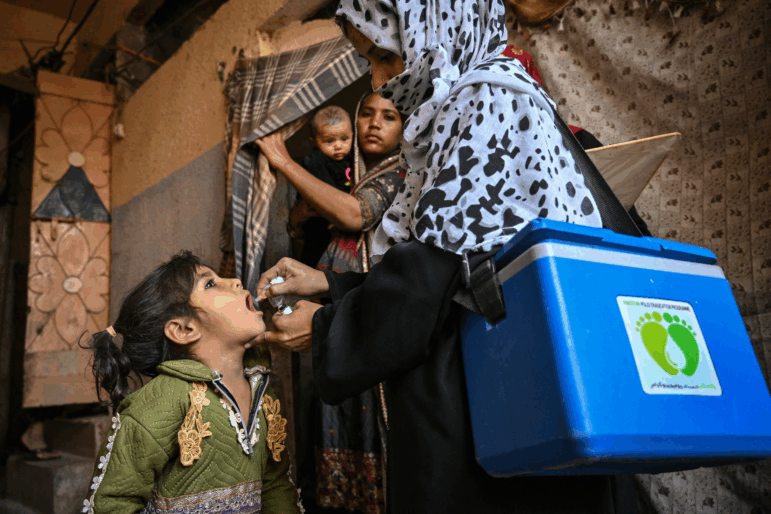 A health worker, right, administers polio drops to a child on the first day of a nationwide polio vaccination campaign, in Karachi on February 3, 2025. A Pakistan police officer travelling to guard polio vaccinators was shot dead on February 3, police said, on the first day of a nationwide immunisation effort after a year of rising cases.