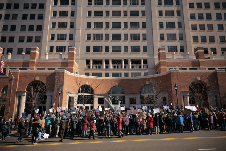A crowd of demonstrators stands outside the NOAA headquarters.
