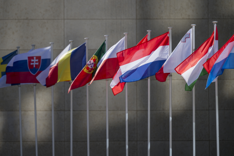 This photo shows a row of flagpoles, each flying a flag of an EU country.