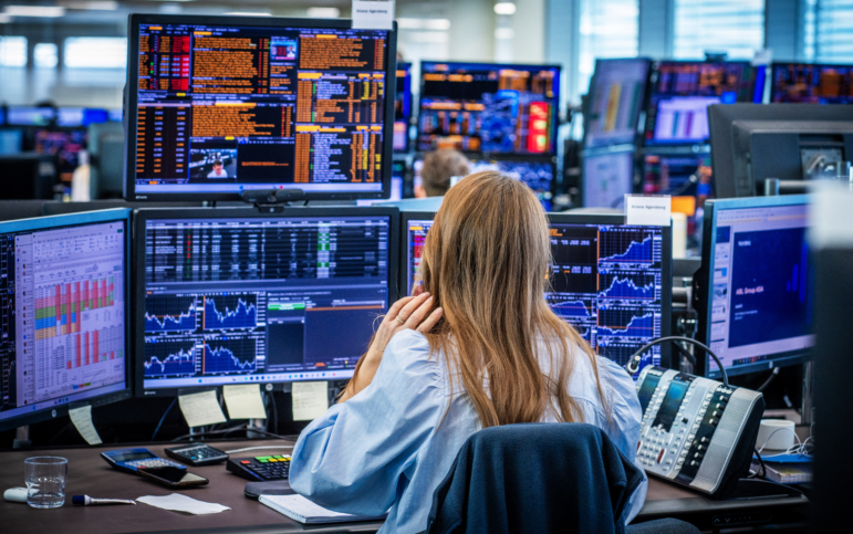 People look at computer screens showing stocks.