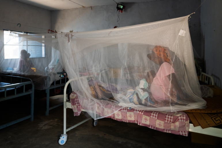 A pregnant woman brought her child to a health clinic in Farchana, Chad. They are sitting under a mosquito net.
