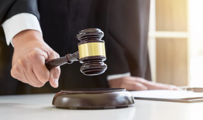 Close up of Male lawyer or judge hand's striking the gavel on sounding block