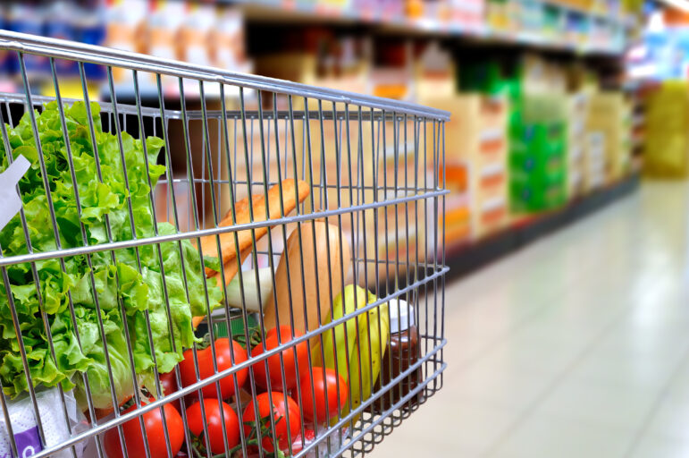 Shopping cart full of food in the supermarket aisle