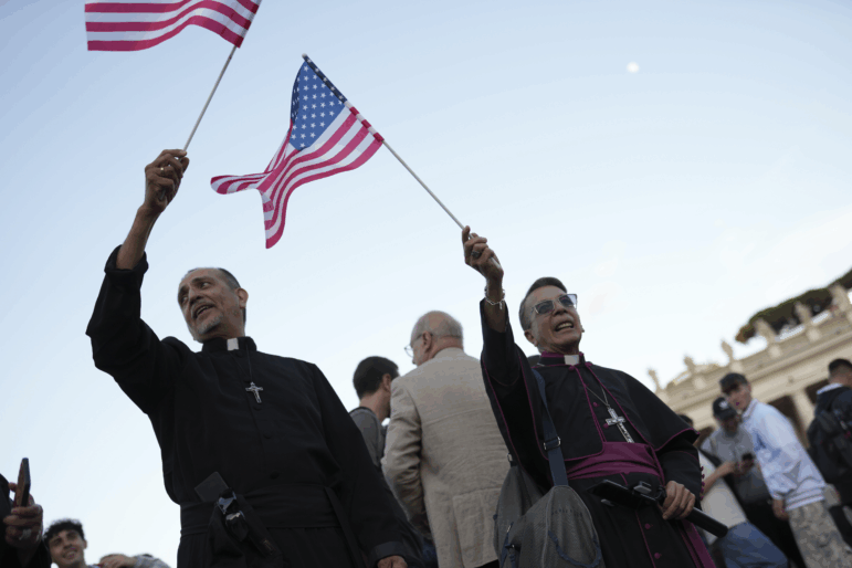 Clerics wave US flags during the speech of the newly elected Pope Leo XIV at the Vatican, Thursday, May 8.