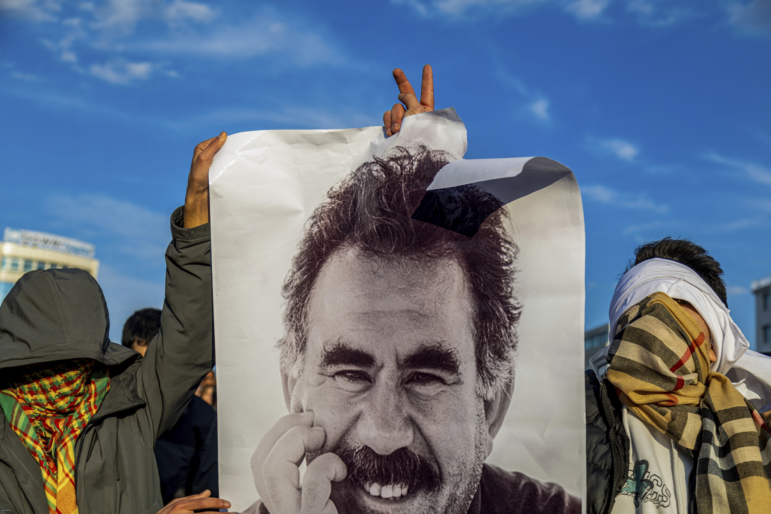 Youngsters hold a photograph of the jailed leader of the rebel Kurdistan Workers' Party, or PKK, Abdullah Ocalan as they gather to watch live on a tv screen a Pro-Kurdish Peoples' Equality and Democracy Party, or DEM, delegation members releasing an statement from Ocalan, in Diyarbakir, Turkey, Thursday, Feb. 27, 2025.