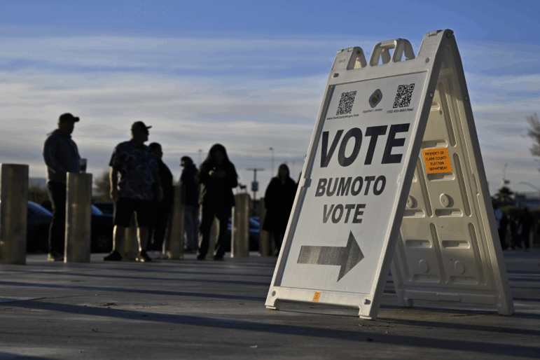 Voters line up to cast their ballots at Allegiant Stadium on Nov. 5, 2024 in Las Vegas, Nevada behind a sign reading "Vote, Bumoto, Vote" - directions in English, Tagalog and Spanish.