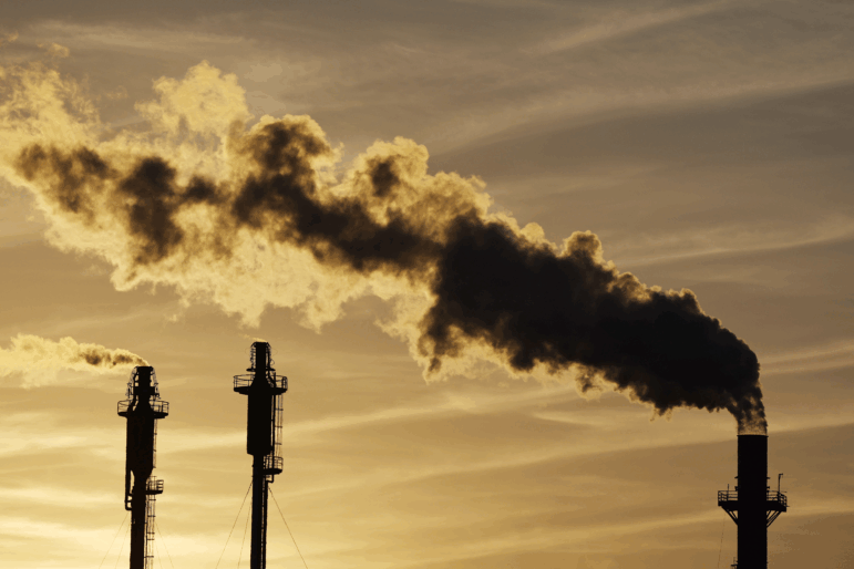 The sun sets behind an oil refinery in California.