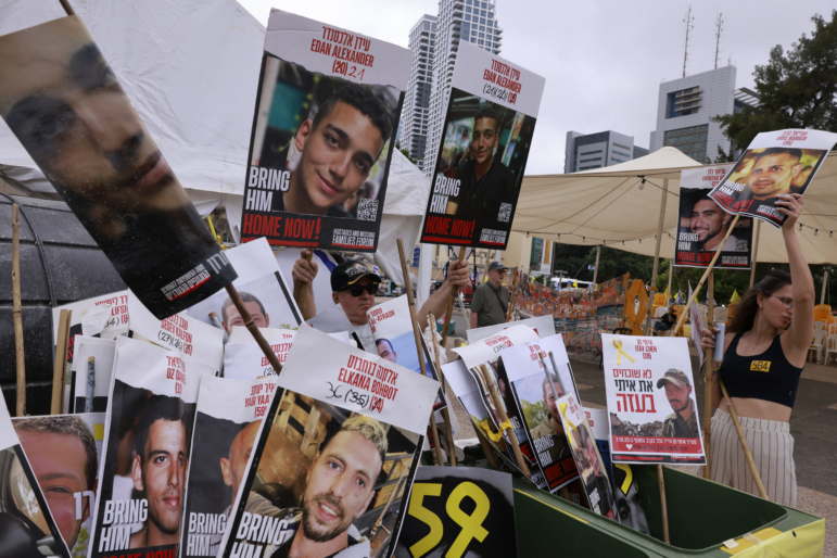A woman holds a poster bearing a portrait of an Israeli hostage held by Hamas in Gaza since October 2023 next to several portaits, including two (C) of Israeli-US captive Edan Alexander, at Hostages Square in Tel Aviv as people wait for his release on May 12, 2025.