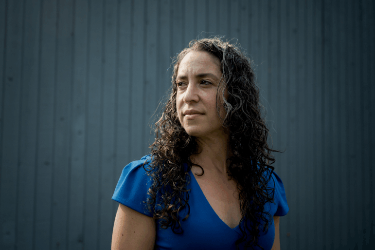 Dr. Maya Bass stands in front of a blue background.