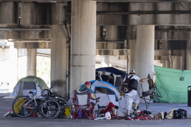 People living in a homeless encampment pick up belongings after Louisiana State police gave instructions for them to move to a different pre-designated location as they perform a sweep in advance of a Taylor Swift concert in New Orleans, Wednesday, Oct. 23, 2024.