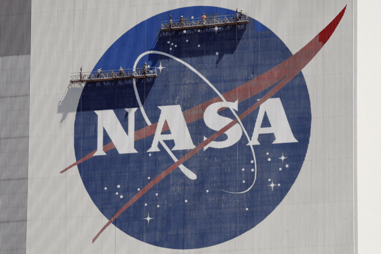 Workers on scaffolding repaint the NASA logo near the top of the Vehicle Assembly Building at the Kennedy Space Center in Cape Canaveral, Fla., May 2020.