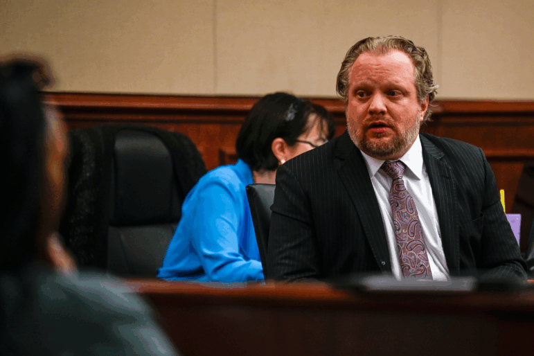 James Craig speaks to people in court, wearing a suit and paisley tie.